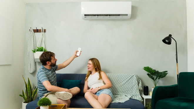 Woman in apartment adjusting heat pump Woman adjusting heat pump