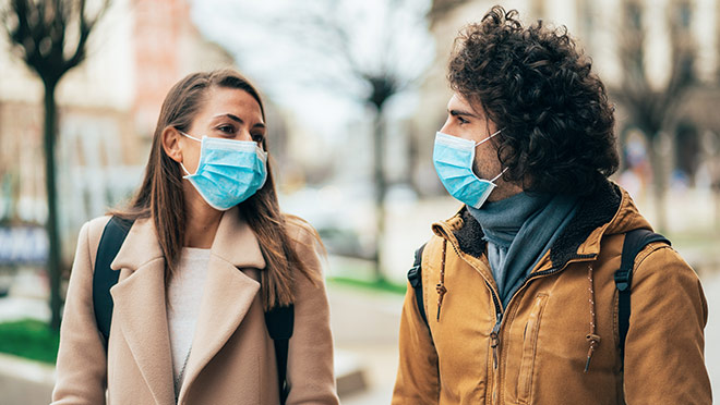 Image of a couple walking and wearing disposable face masks