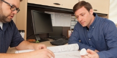 Consultant and engineer working in an office reviewing technical drawings.
