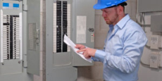 Engineer wearing hardhat checking control panel. 