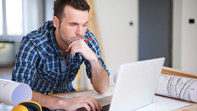 Image of engineer with technical drawings and laptop