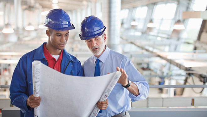 Image of engineers inside a factory looking over drawings