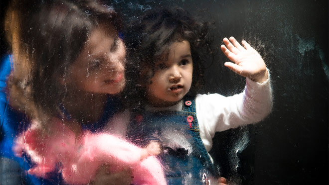 Girl and mother behind glass waving goodbye Girl and mother behind glass waving goodbye