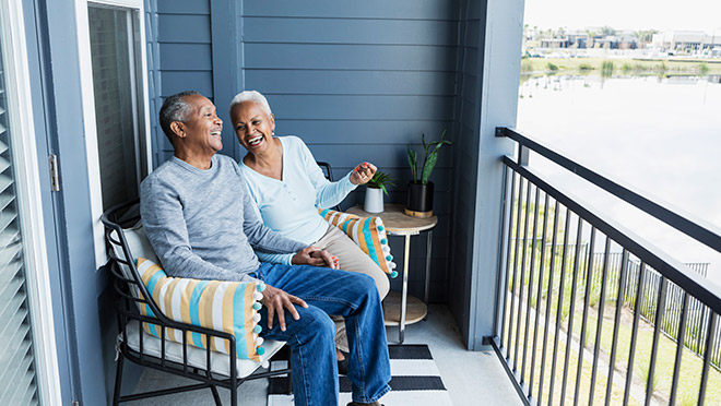 Happy couple sitting together on their condo's balcony