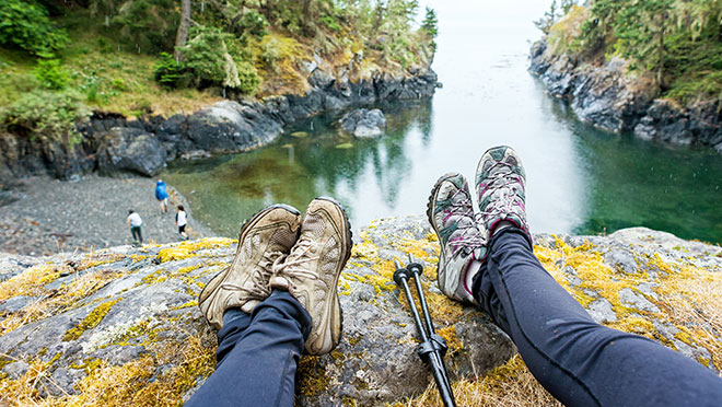 Image of hikers sitting on the edge of a cliff on the B.C. coast Image of hikers sitting on the edge of a cliff on the B.C. coast