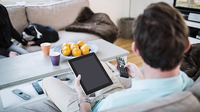 Image of a man using a tablet computer and watching TV