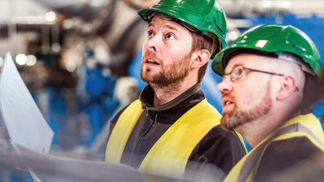 Two men looking up wearing hard hats and safety vests