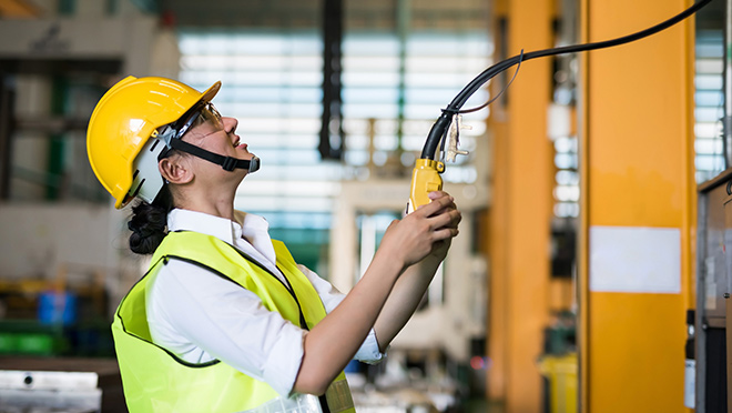 An industrial worker in a high-vis vest and hardhat