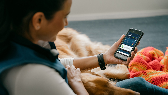 Woman holds smartphone, looking at the HydroHome app
