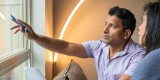 Two people in a house in front of a window discussing energy efficiency.