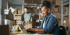 Male and Female Warehouse Managers Checking Inventory on Laptop