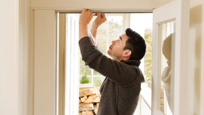 Man applying weather stripping in a doorway Man applying weather stripping in a doorway