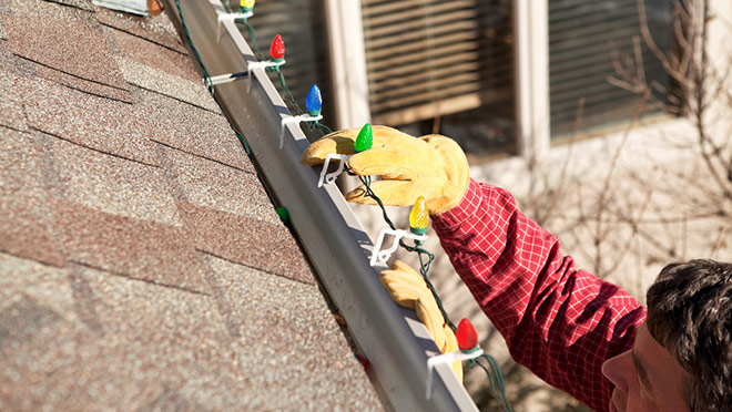 Image of man on a ladder installing lights on a house roof Image of man on a ladder installing lights on a house roof