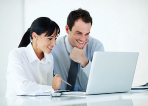 Two coworkers looking eagerly at a laptop