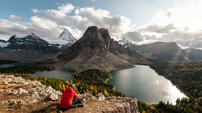 Hiker in front of mount assiniboine with rocky mountains and lake