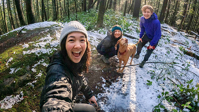 Three people and a dog hiking on Vancouver's North Shore in light winter snow