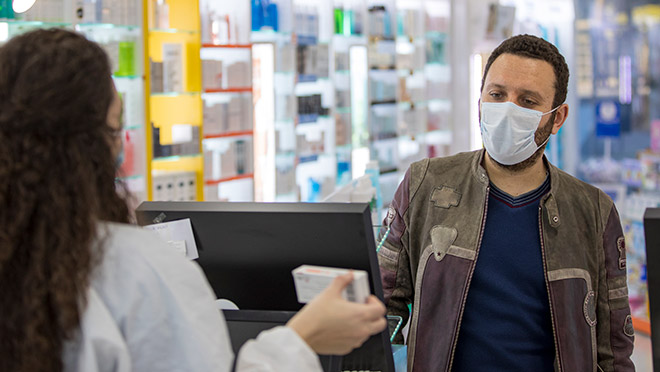 Image of a shop worker and customer wearing masks and following social distance guidelines
