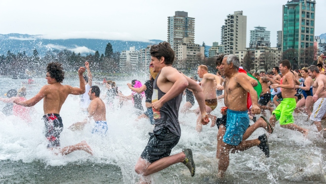 Swimmers at Vancouver Polar Bear Swim A crowd runs into the water at the Vancouver Polar Bear Swim at English Bay under cloudy skies