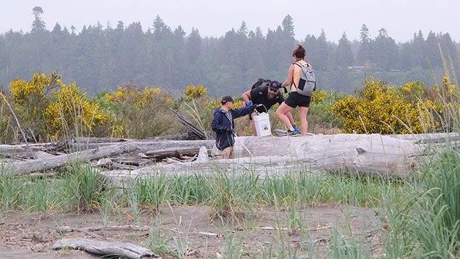 Team Power Smart members unearth beach trash alongside a log at Iona Beach Regional Park in Richmond, B.C.