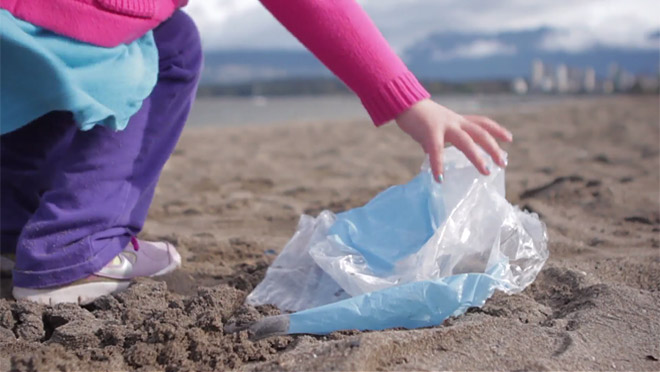 Image of young child picking up trash on a Vancouver beach Image of young child picking up trash on a Vancouver beach