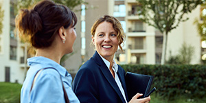A female homeowner consults a tablet held by a technician, discussing the settings of an external heat pump unit. 