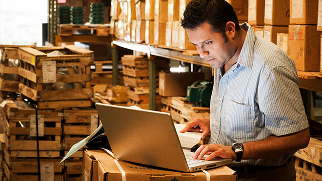 Image of warehouse worker using a laptop computer Image of warehouse worker using a laptop computer