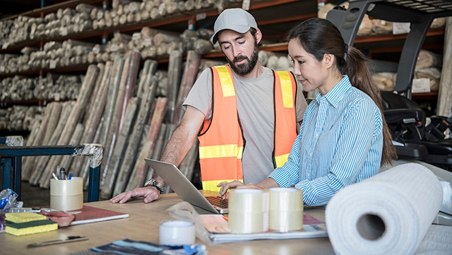 Image of two warehouse workers using a laptop computer