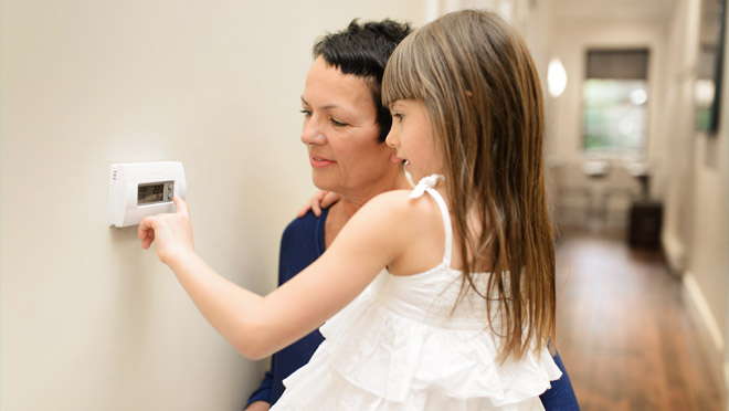 Child with mother turning down a thermostat Child with mother turning down a thermostat