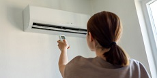 Woman in apartment adjusting heat pump