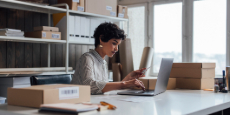 Woman logging product information on laptop in office