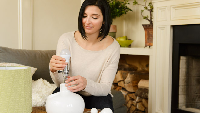 Woman switching to an LED light bulb Woman switching to an LED light bulb