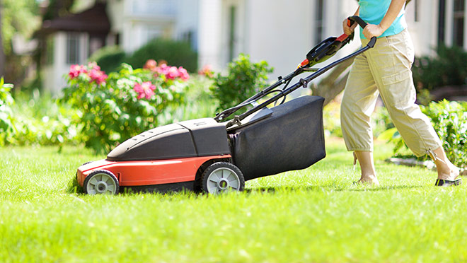 Image of a woman mowing a lawn with an electric lawnmower