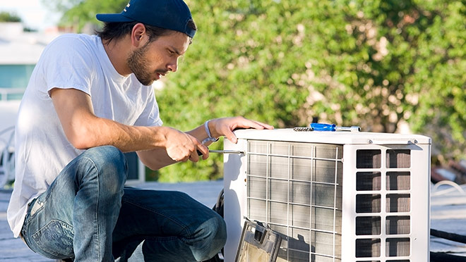 A technician installs a heat pump on a residential rooftop