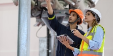 Two workers wearing hard hats checking equipment
