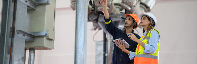 Two workers wearing hard hats checking equipment.