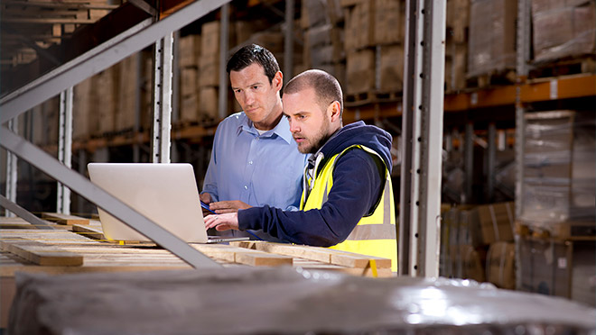 Image of workers using a laptop computer in a warehouse