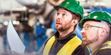 Workers wearing hardhats reviewing plans