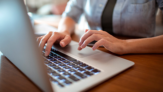 Hands typing on a laptop computer