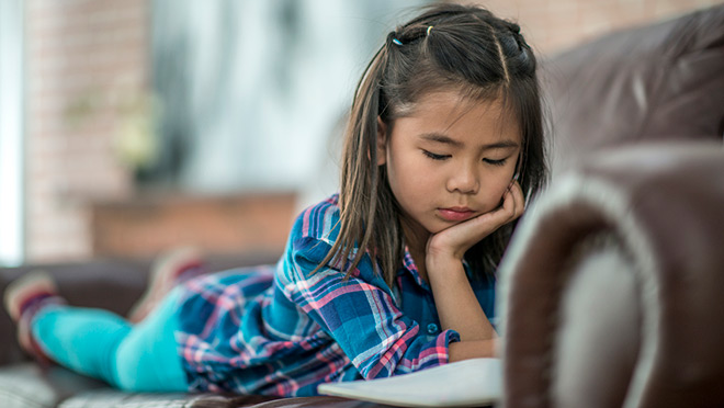 Image of young girl reading on a couch