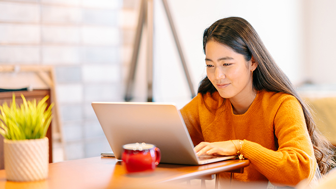 A young woman is using a laptop comfortably in the living room at home.