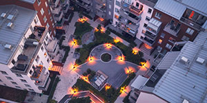 Aerial view of apartment buildings around an inner yard in the evening.