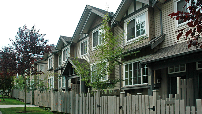 Photo of a city street next to residential homes Photo of a city street next to residential homes
