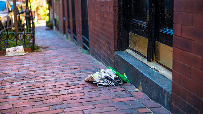 Image of newspapers piled outside of a door Image of newspapers piled outside of a door
