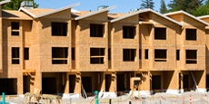 A construction site featuring a row of partially built townhouses with wooden frames.
