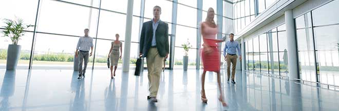 Business people walk through an office building foyer Business people walk through an office building foyer