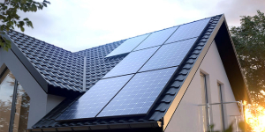 Solar panels on the roof of a house with sunlight in the background.