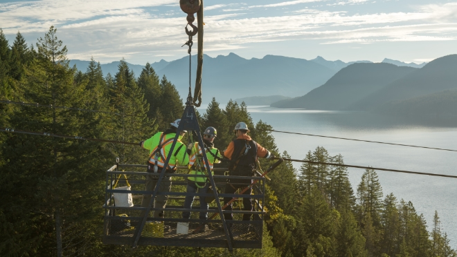 Detonation specialists work with a BC Hydro power line technician to secure the detonation device on the conductor. 