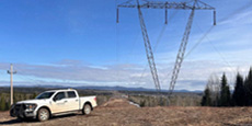 BC Hydro truck parked near a large power transmission tower in a rural landscape. BC Hydro truck parked near a large power transmission tower in a rural landscape.