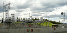 Capacitor station with metal structures, transformers, and power lines enclosed by fencing under a cloudy sky. Capacitor station with metal structures, transformers, and power lines enclosed by fencing under a cloudy sky.