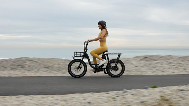 Woman riding a RadRunner 2 e-bike at the seaside